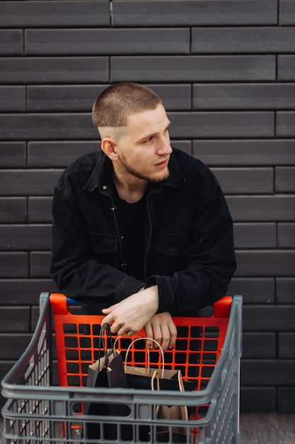 Junger Mann mit Taschen und Trolley am Black Friday