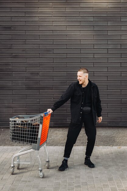 Junger Mann mit Taschen und Trolley am Black Friday