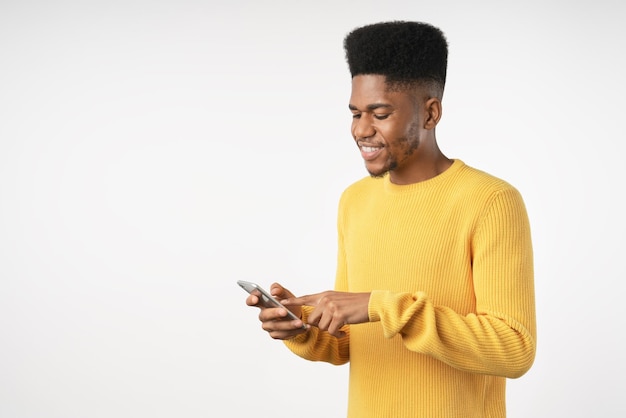 Junger Mann mit Telefon und Blick auf Smartphone isoliert auf weißem Studiohintergrund