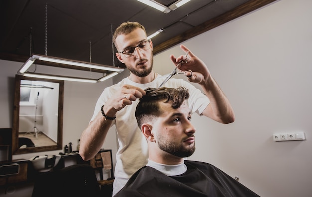 Junger Mann mit trendigem Haarschnitt am Friseurladen.