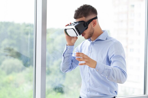 Junger Mann mit Virtual-Reality-Brille im modernen Coworking-Studio.
