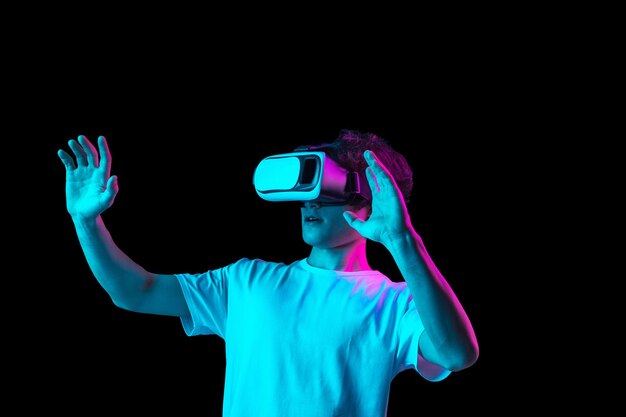 Junger Mann mit VR-Headset isoliert vor dunklem Hintergrund in Neonlicht