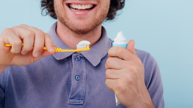 Junger Mann mit Zahnbürste und Zahnpasta lächelnd