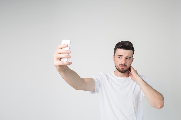 Junger Mann nimmt Selfie mit Smartphone in der Hand