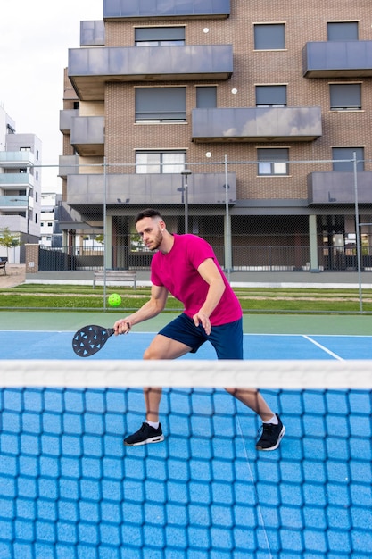 Junger Mann Pickleball-Spieler spielt Pickleball im Gericht