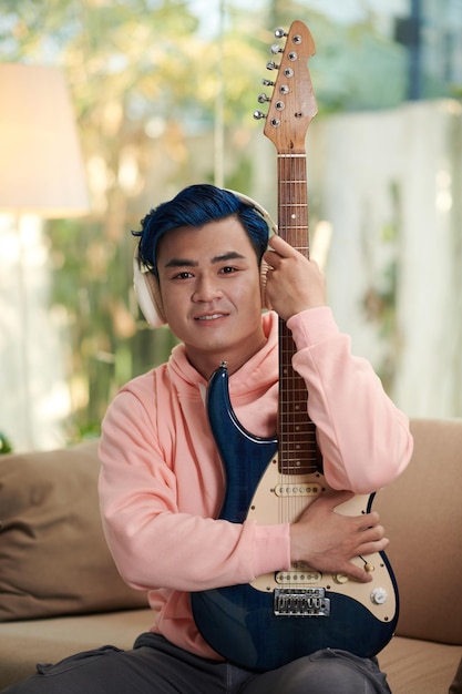 Junger Mann posiert mit E-Gitarre