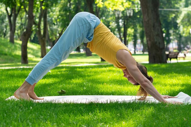 Junger Mann praktiziert Yoga im Park Yoga-Asanas im Stadtpark sonniger Tag Konzept der Meditation, Wohlbefinden und gesunder Lebensstil