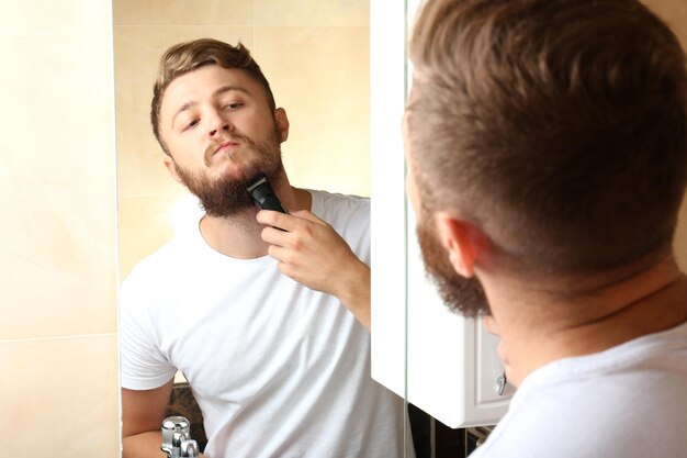 Junger Mann rasiert sich im Badezimmer den Bart