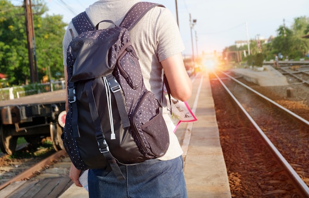 Foto junger mann reisenden mit rucksack am bahnhof mit einem reisenden, reise-und erholungs-konzept