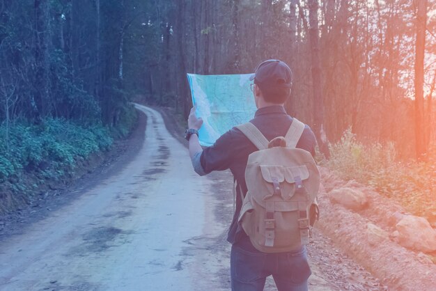 Junger Mann-Reisender mit Kartenrucksackentspannung im Freien mit felsigen Bergen auf Hintergrund Sommerferien und Lebensstil, die Konzept wandern