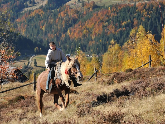 Junger Mann reitet ein Pferd in den Bergen