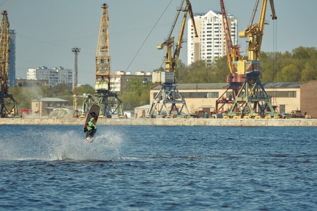 Junger Mann reitet Wakeboard auf einem Sommersee.