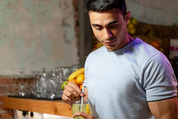 Junger Mann schaut in seinen frischen Cocktail