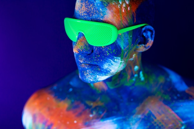 Foto junger mann schreit. fluoreszierende farbe auf gesicht und muskulösem oberkörper, im studio mit uv-licht aufgenommen