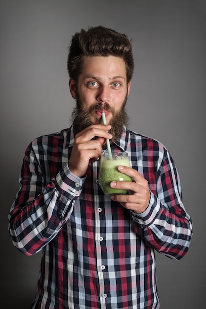 Foto junger mann sieht wunderlich aus, als er köstlichen grünen spinat-smoothie trinkt