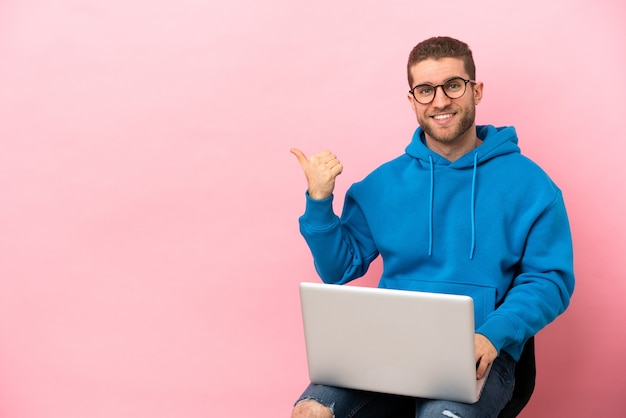 Junger Mann sitzt auf einem Stuhl mit Laptop zur Seite, um ein Produkt zu präsentieren