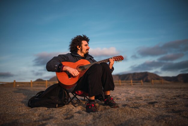 Junger Mann spielt Gitarre am Strand