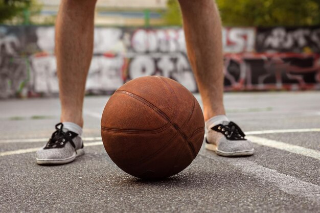 Junger Mann spielt mit einem Basketball im Freien Aktives Lifestyle-Konzept