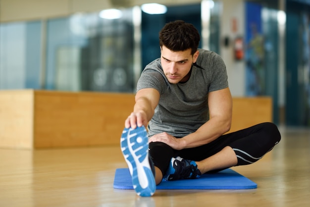 Junger Mann streckt ihre Beine im Fitnessstudio.