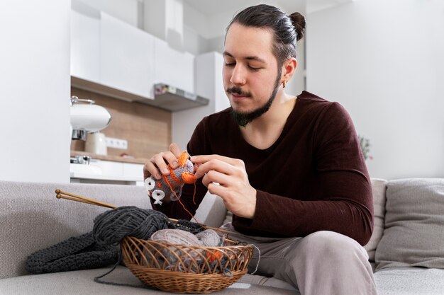 Junger Mann strickt beim Entspannen