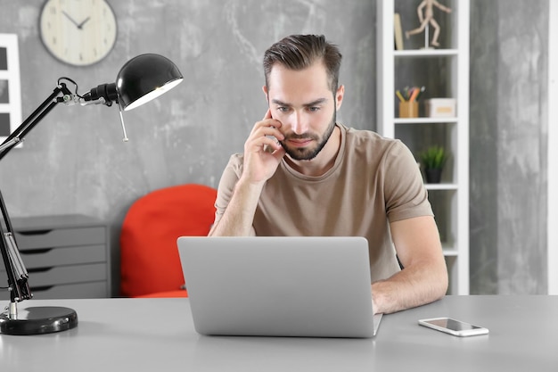 Junger Mann sucht Informationen mit Laptop am Tisch