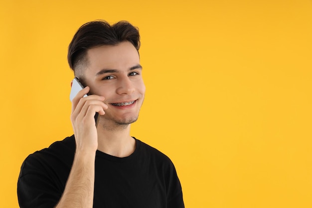 Junger Mann telefoniert auf gelbem Hintergrund