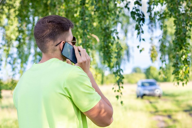 Junger Mann telefoniert in der Nähe des Autos