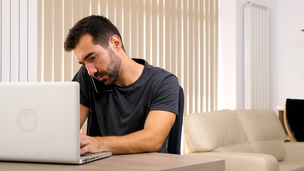 Junger Mann telefoniert, während er im Büro ist. Intelligenter Mann, der sich um das Geschäft kümmert.