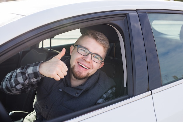 Junger Mann testet neues Auto und zeigt Daumen hoch