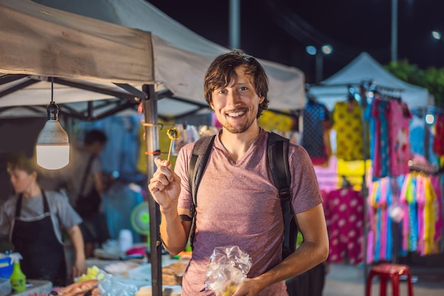 Junger Mann Tourist auf dem asiatischen Lebensmittelmarkt der Walking Street