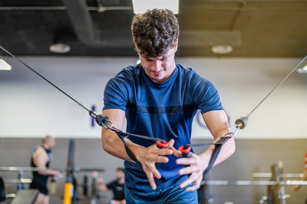 Junger Mann trainiert an einer Multistation im Fitnessstudio für Arm- und Schultermuskeln. Fitnesstraining im Fitnessstudio