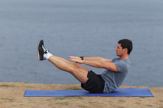 Junger Mann trainiert im Freien und macht Sit-ups im Freien