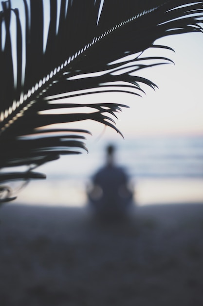 Junger Mann üben Yoga am Strand bei Sonnenuntergang.