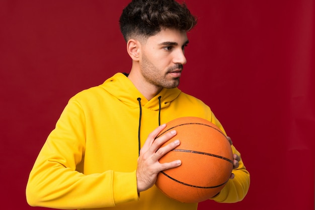 Junger Mann über getrennter Wand mit Kugel des Basketballs