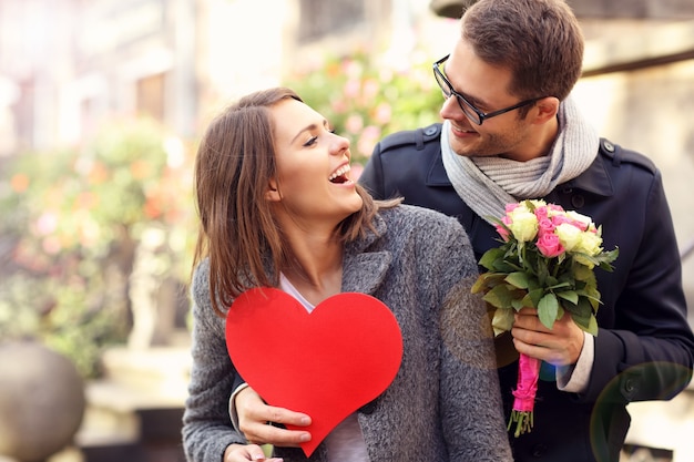 junger Mann überraschende Frau mit Blumen und Herz
