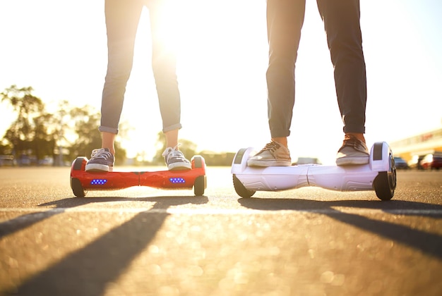 Junger Mann und Frau, die auf dem Hoverboard in den Parkinhaltstechnologien fahren, sind eine neue Bewegung