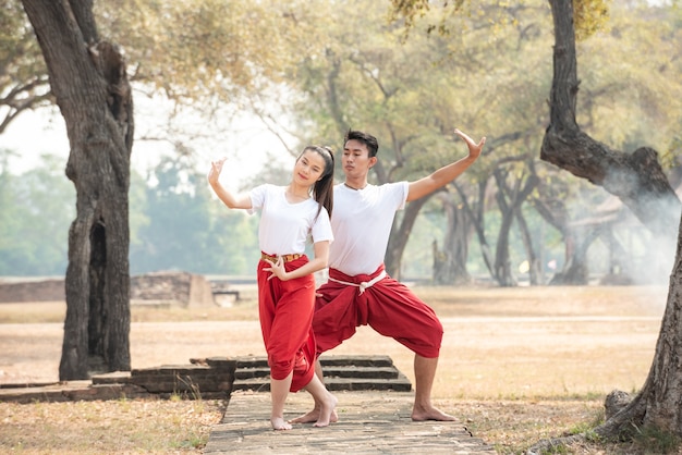 Junger Mann und Frau, die einen traditionellen thailändischen Tanz üben