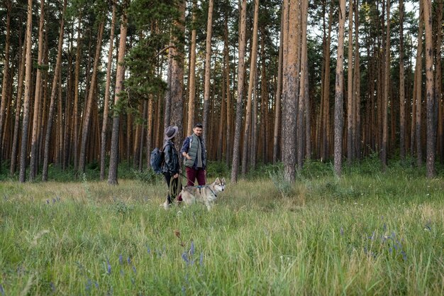 Junger Mann und Frau, die mit heiserem Hund spazieren gehen