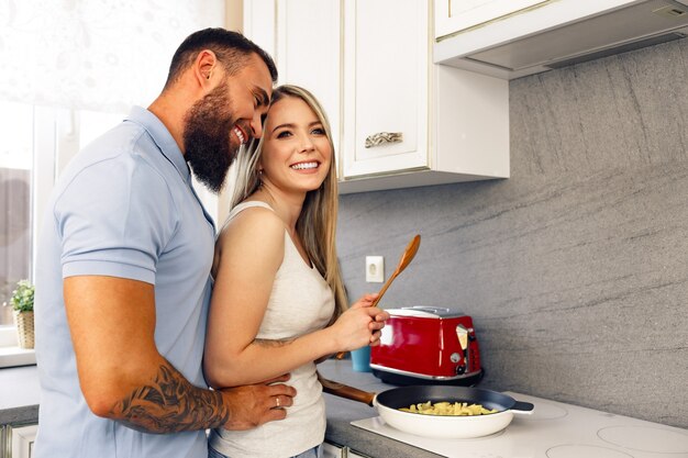 Junger Mann und Frau, die zusammen Essen in der Küche kochen, glückliches Paar, das Essen zubereitet?