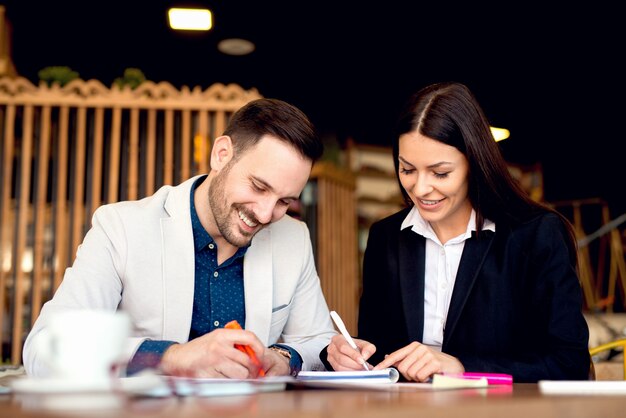 Junger Mann und Frau sitzen am Tisch und machen sich Notizen