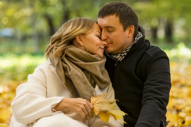 Junger Mann und Frau umarmen sich sanft im Herbstpark Schönes Paar mit goldenen Herbstblättern Liebe und Treue Nahaufnahme