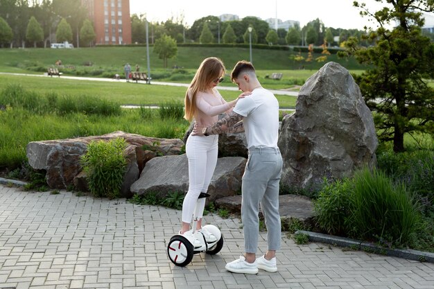 Junger Mann und junge Frau, die auf dem Hoverboard im Park reiten