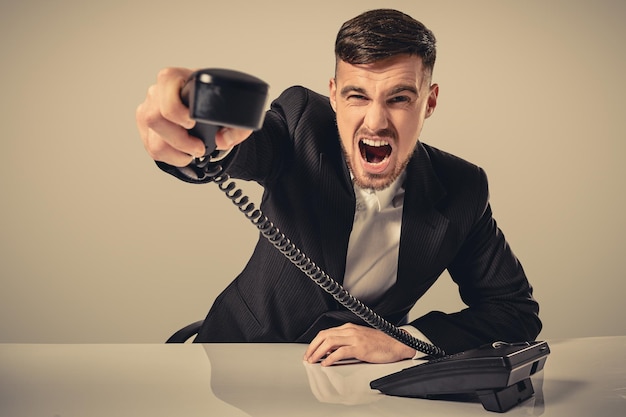 Junger Mann wählt die Telefonnummer, während er im Büro sitzt