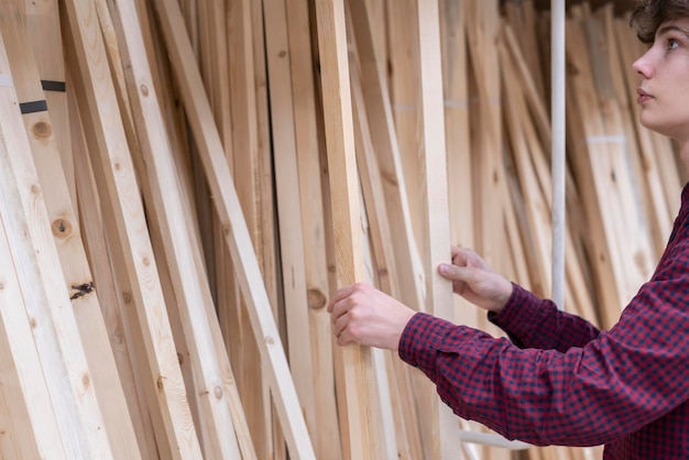 junger Mann wählt Holzbrett im Baumarkt aus b