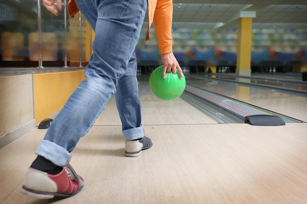 Junger Mann wirft Ball im Bowlingclub