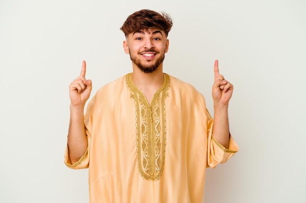 Junger marokkanischer Mann, der auf Weiß isoliert ist, zeigt mit beiden Vorderfingern oben eine leere Stelle an.