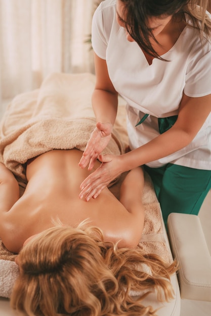 Junger Massagetherapeut, der einer Klientin eine Entspannungsmassage gibt.