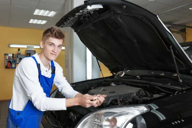 Junger Mechaniker, der Auto in der Karosseriewerkstatt repariert