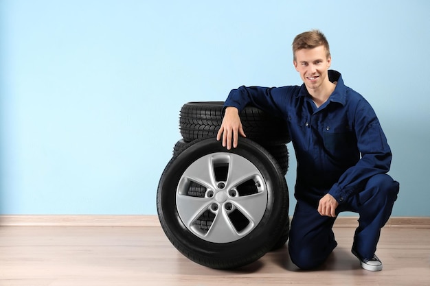 Junger Mechaniker in Uniform mit Rädern auf blauem Hintergrund