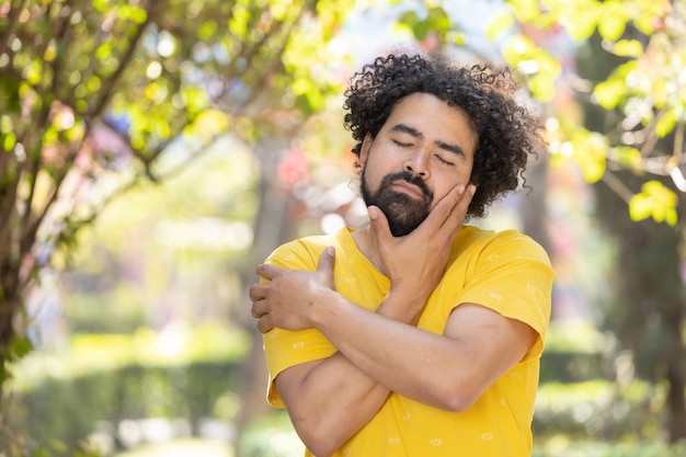 Junger Mexikaner mit Bart und Afro, der sich selbst umarmt, Selbstliebekonzept